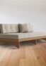 Modern wooden sofa with beige cushions, handcrafted from solid wood with a minimalist Scandinavian design.